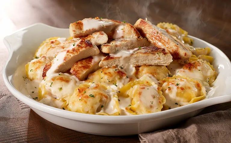 Chicken Tortelloni Alfredo — Asiago cheese-filled tortelloni baked in our homemade alfredo with a blend of Italian cheeses…